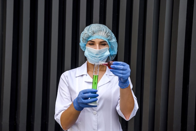 Química mulher com tubos de ensaio e uniforme de proteção fazendo experimento com duas substâncias