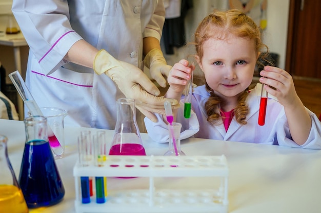 Químico de escola ruiva inteligente em óculos e vestido médico branco fazendo experiências científicas química, misturando diferentes soluções químicas em sala de aula de laboratório