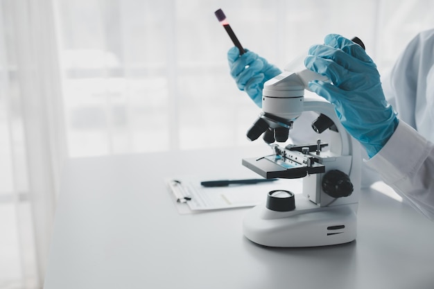 Un químico está usando un microscopio para buscar sustancias químicas de la sangre en un tubo de ensayo Un experimento científico está buscando respuestas biológicas en un laboratorio.
