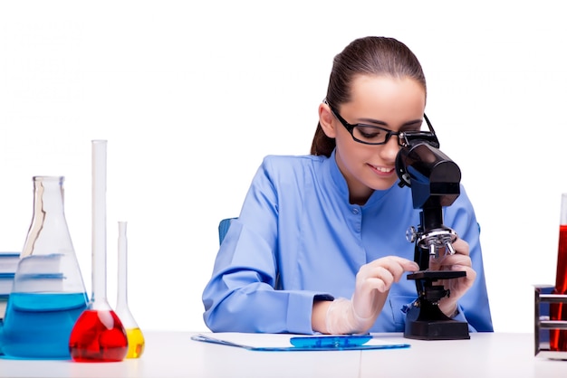 Químico de laboratorio trabajando con microscopio y tubos.