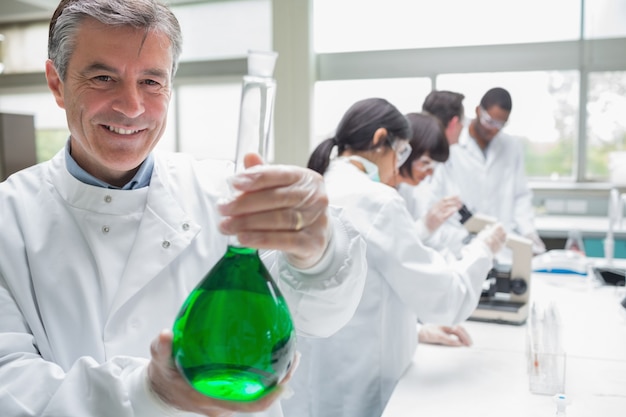 Químico sonriendo y sosteniendo el vaso de precipitados