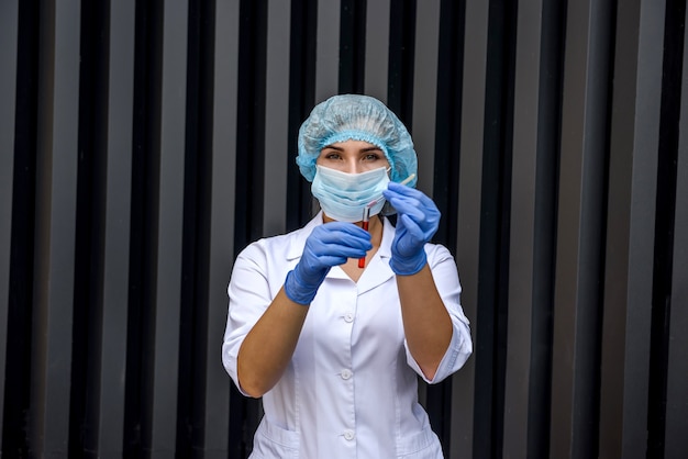 Foto químico con tubos de ensayo posando en laboratorio mientras hace experimentos científicos