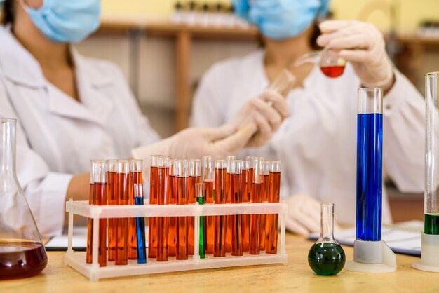 Químicos trabalhando em laboratório. mulheres jovens em uniformes de proteção com tubos de ensaio fazendo experiências