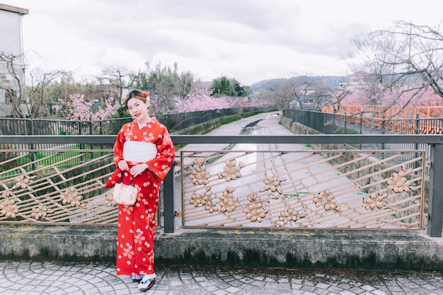 Quimono vestindo da mulher asiática com flores de cerejeira, sakura em Japão.