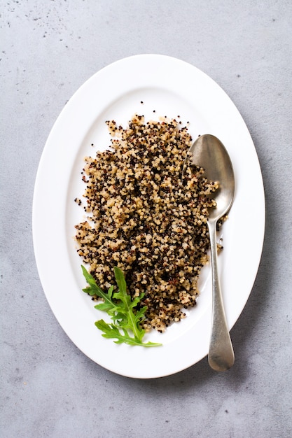 Quinoa branca, vermelha e preta cozida em chapa branca sobre fundo cinzento rústico, vista de cima, lugar para receitas de texto ou menu. superalimento vegan, alimentação saudável e nutrição ou conceito de dieta.