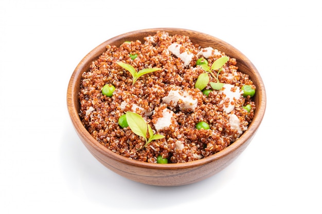 Quinoa Brei mit grüner Erbse und Huhn in der Holzschale lokalisiert auf einem weißen Hintergrund.