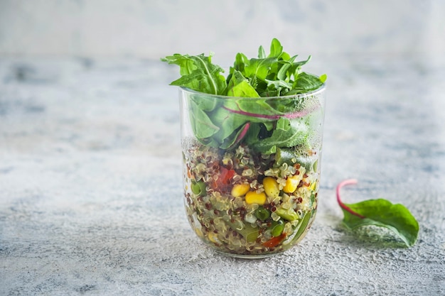 Quinoa com legumes em um copo de vidro com folhas de alface