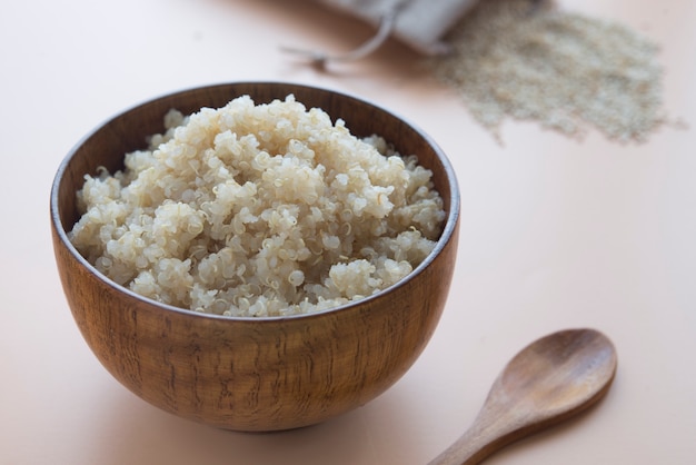 Quinoa cozida na tigela e colher de pau no marrom