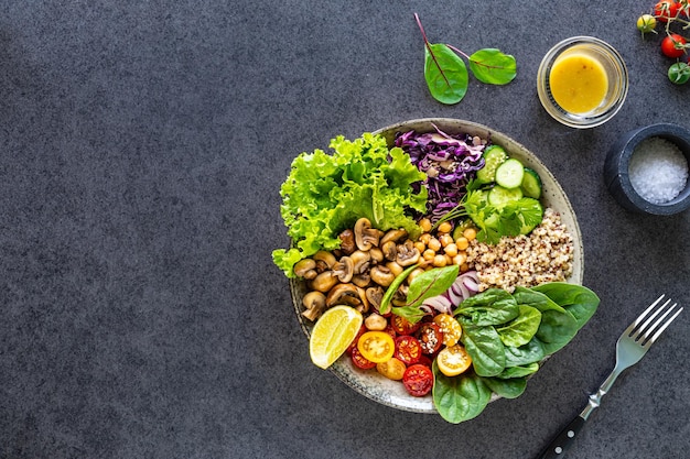 Quinoa-Pilze, Salat, Rotkohl, Spinat, Gurken, Tomaten, eine Schüssel Buddha auf dunklem Hintergrund. Köstliches, ausgewogenes Ernährungskonzept