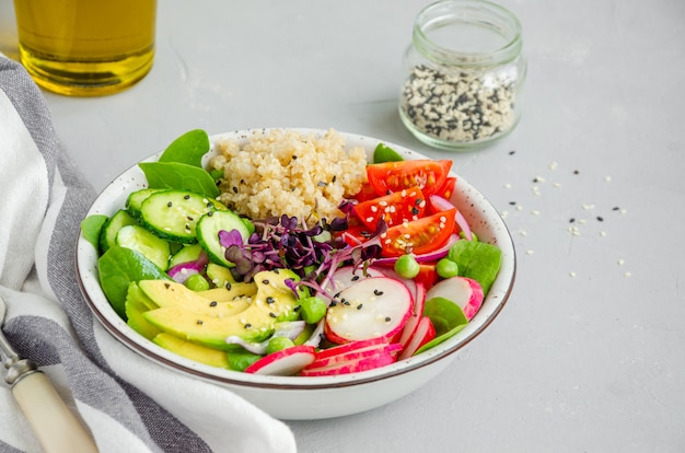 Quinoa-Salat mit frischem Gemüse, Spinat, grünen Erbsen, Microgreens und Sesam in einer Schüssel