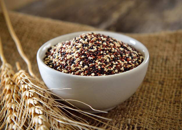 Quinoa-Samen in der Schüssel auf Holz