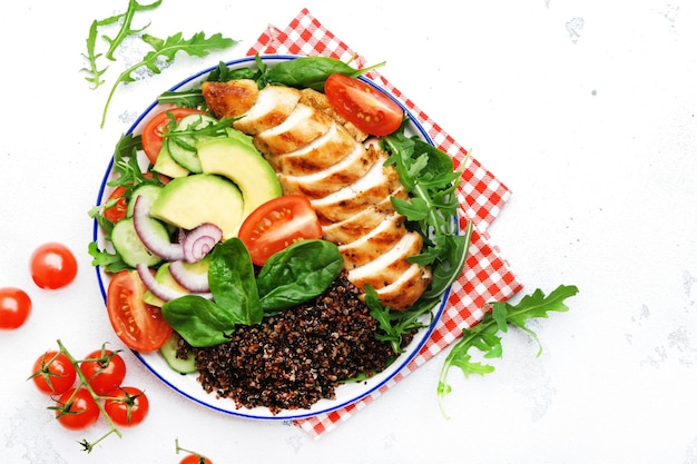 Quinoa vermelha de carne de frango grelhada e salada de legumes fresca com tomate, abacate e espinafre comida de dieta cetogênica de desintoxicação saudável vista superior de fundo branco