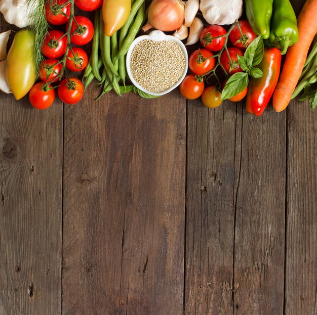 Quinua en un cuenco y verduras frescas en una vista superior de la mesa de madera con espacio de copia