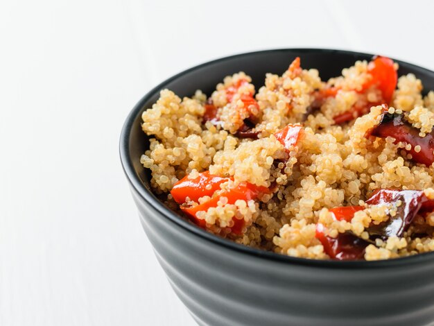 Quinua hervida con pimienta al horno sobre una mesa blanca. Plato vegetariano.