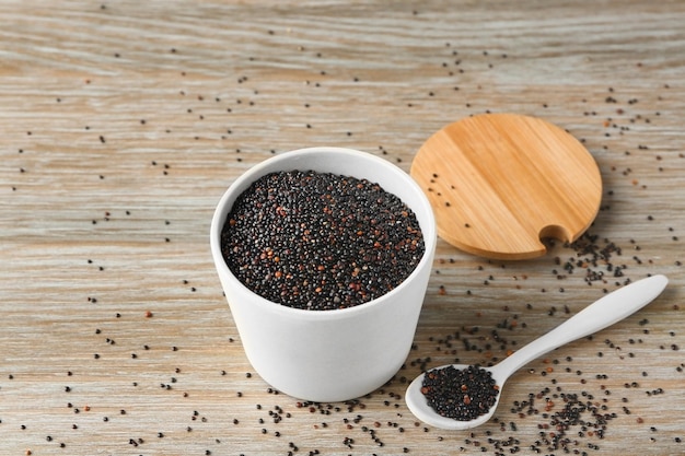 Quinua negra en taza de cerámica y cuchara en la mesa de la cocina