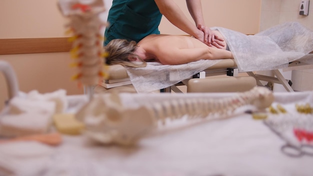 Quiropráctico masajeando a una mujer acostada en una mesa de masajes, salud y concepto médico