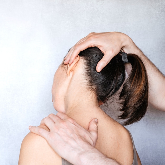 Foto un quiropráctico realizando una manipulación en el cuello de la mujer y administrando ajustes espinales para revivir el dolor de cuello.