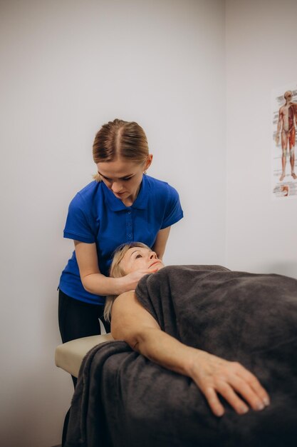 Quiroprático profissional ou fisioterapeuta ajuda a curar as costas de uma mulher idosa O médico corrige o paciente deitado em um sofá de uma clínica de reabilitação moderna Conceito de reabilitação física