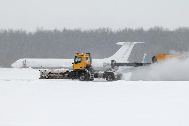 Quitanieves del aeródromo de limpieza de la pista de aterrizaje en el aeropuerto en una severa tormenta de nieve