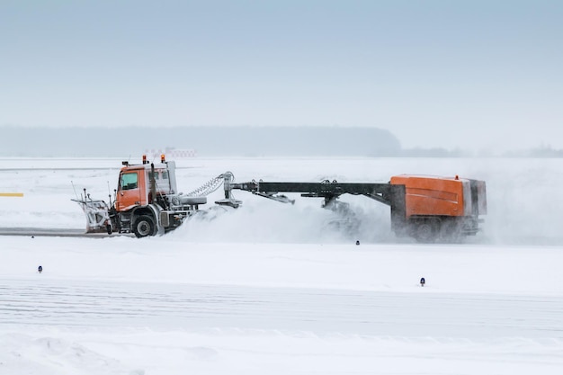 Quitanieves limpia la calle de rodaje del aeropuerto en una tormenta de nieve