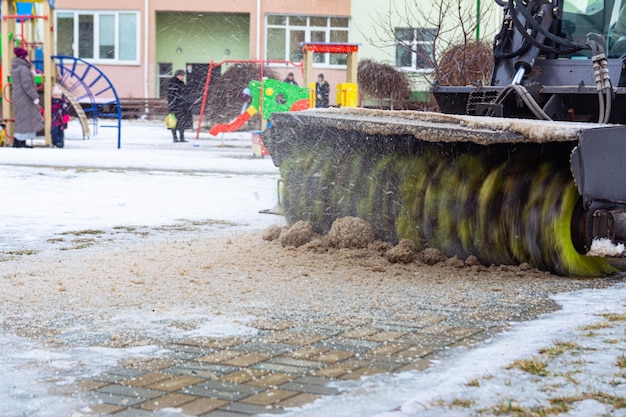 Un quitanieves quita la nieve de la acera en el patio de un edificio residencial