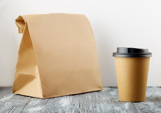 Quitar la taza de café de papel con bolsa de almuerzo sobre fondo de madera gris