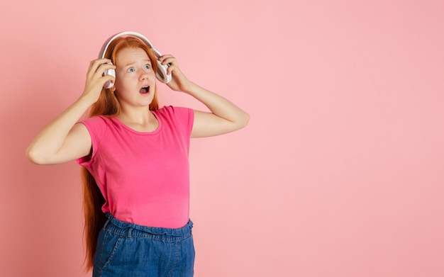 Quitarse los auriculares retrato de niñas adolescentes caucásicas sobre fondo de estudio de color rosa coral