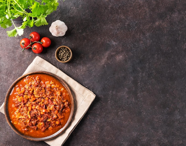 Rabada cozida com legumes em uma placa de madeira em um fundo escuro com tomates frescos e ervas Ensopado de carne O conceito de cozinha tradicional espanhola