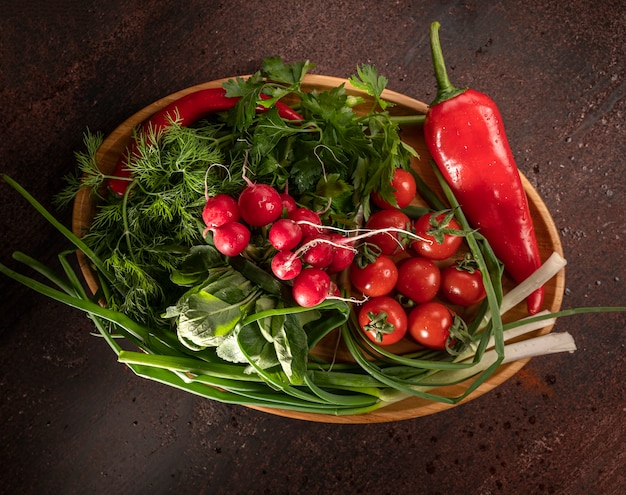 Rábano, cebolla verde, pimiento, tomate, eneldo, perejil sobre una superficie de madera