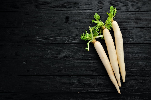 Rábano Daikon sobre un fondo negro. Rábano. Vegetales. Vista superior. Espacio libre para su texto.