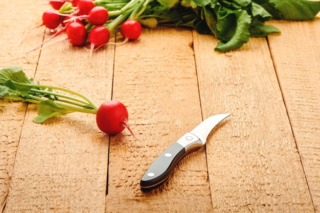 Rábano maduro fresco con hojas y cuchillo en la mesa antigua Verduras vitamínicas Cosecha fresca del jardín Vista de cerca con DOF superficial