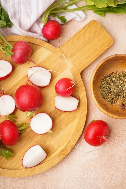 Rábano rojo fresco en tabla de cortar y especias en un fondo beige