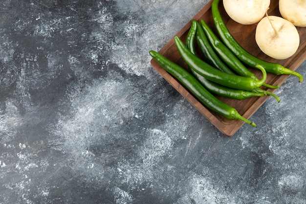 Rábanos blancos enteros colocados con ají verde sobre una mesa de mármol.