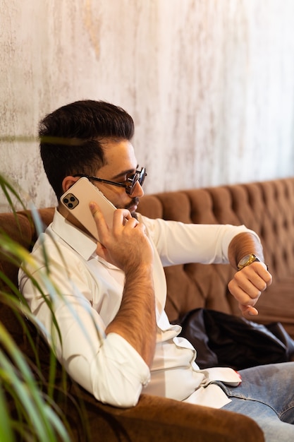 Árabe exitoso hombre de negocios o trabajador con camisa blanca con barba llamando con su teléfono cerca de su