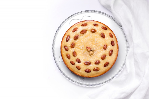 Árabe trata el pastel de Basbus con sémola, coco y almendras sobre un fondo blanco.