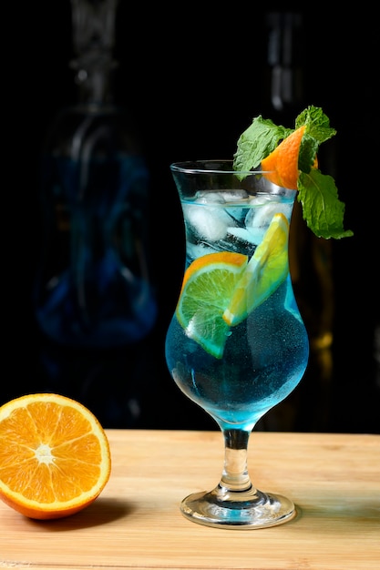 Rabo de rabo de Curaçao azul, margarita azul uma em uma placa de madeira borrado garrafas de bebida em um fundo escuro