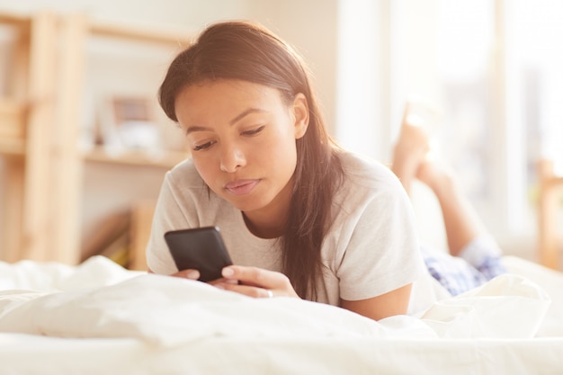 Raça mista, mulher, usando telefone, cama