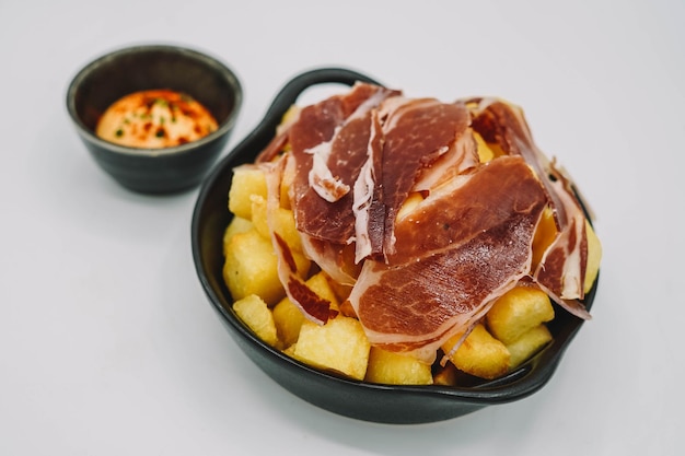 Ração de patatas bravas espanholas com presunto ibérico.