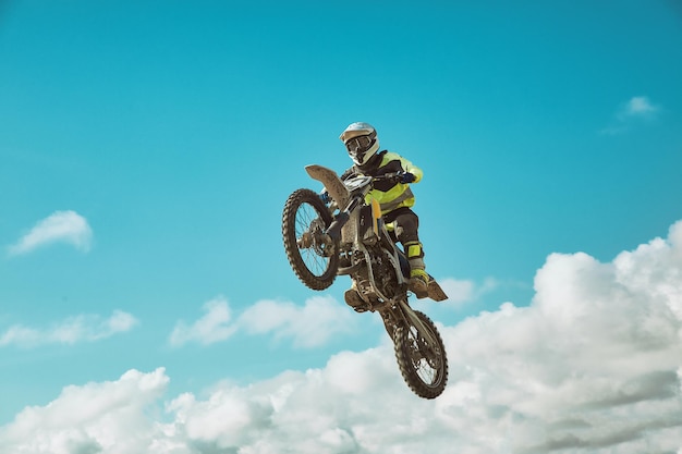 Racer en motocicleta dirtbike motocross crosscountry en vuelo salta y despega en trampolín contra el cielo Concepto activo descanso extremo