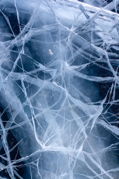 Rachaduras brancas no gelo espesso. A textura natural do gelo. Vertical.