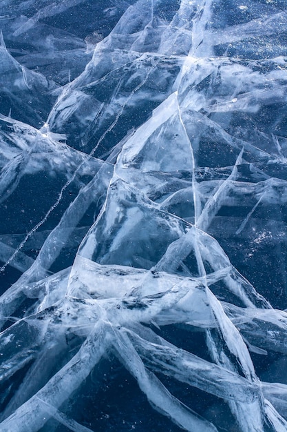 Rachaduras naturais no gelo azul do lago. Muitas rachaduras bonitas no gelo de várias camadas espesso.