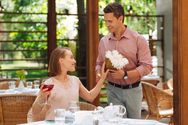 Racimo de flores. Sonriente mujer radiante teniendo ramo de bonitas flores blancas de marido cariñoso