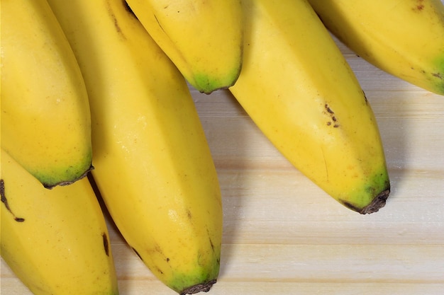 Racimo de plátano en la tabla de cortar de madera de cerca Aperitivo natural saludable