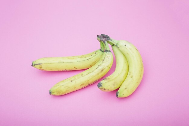 Foto un racimo de plátanos en un minimalismo de fondo rosa.