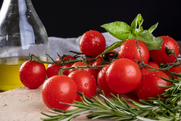 Racimo de tomates con hojas de albahaca y ramas de romero.