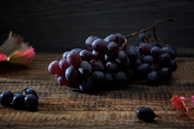 Foto racimo de uvas y hojas de parra en una vieja mesa de madera.