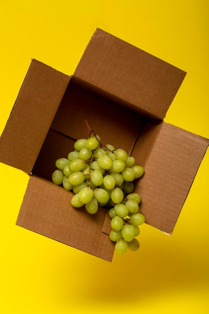 Un racimo de uvas maduras en una caja de cartón sobre un fondo amarillo