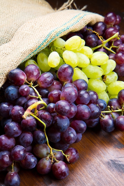 Racimo de uvas negras y verdes sobre fondo de madera