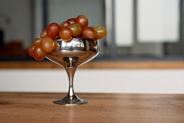 Un racimo de uvas rojas maduras y jugosas en un recipiente de metal sobre una mesa de madera Comida alimentación saludable Enfoque selectivo suave