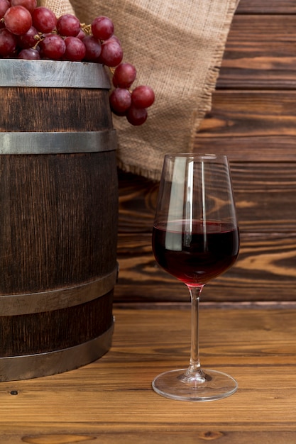 Foto racimo de uvas sobre barril de madera con vaso